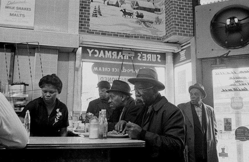A group of elderly African American men eat lunch at the counter of Sure's Pharmacy, in Chicago, IL, 1965