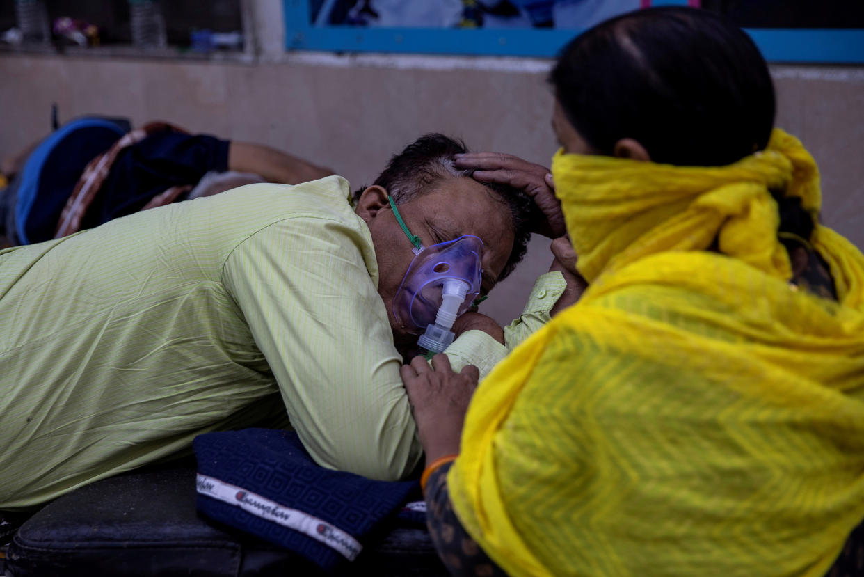 A woman takes care of her husband, who is suffering from COVID-19, as he waits to get admitted outside the casualty ward at Guru Teg Bahadur hospital in New Delhi on April 23, 2021.