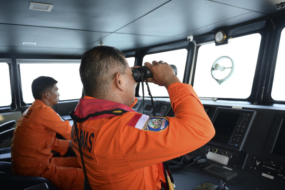 Un trabajador de la Agencia Nacional de Búsqueda y Rescate utiliza prismáticos para tratar de avistar a una embarcación con refugiados rohinya que naufragó ante Aceh Occidental, Indonesia, el 21 de marzo de 2024. (AP Foto/Reza Saifullah)