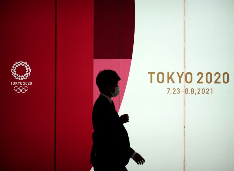 A man wearing a protective face mask walks by an advertising of Tokyo 2020 Olympic Games