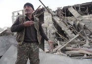 A man stands near his neighbour's house destroyed by shelling by Azerbaijan's artillery during a military conflict in Stepanakert, the separatist region of Nagorno-Karabakh, Saturday, Oct. 17, 2020. The latest outburst of fighting between Azerbaijani and Armenian forces began Sept. 27 and marked the biggest escalation of the decades-old conflict over Nagorno-Karabakh. The region lies in Azerbaijan but has been under control of ethnic Armenian forces backed by Armenia since the end of a separatist war in 1994. (AP Photo)