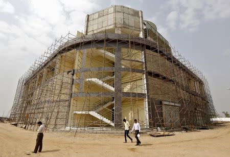 Engineers walk past a cooling system plant under construction inside Gujarat International Finance Tec-City (GIFT) at Gandhinagar, in the western Indian state of Gujarat, April 10, 2015. REUTERS/Amit Dave