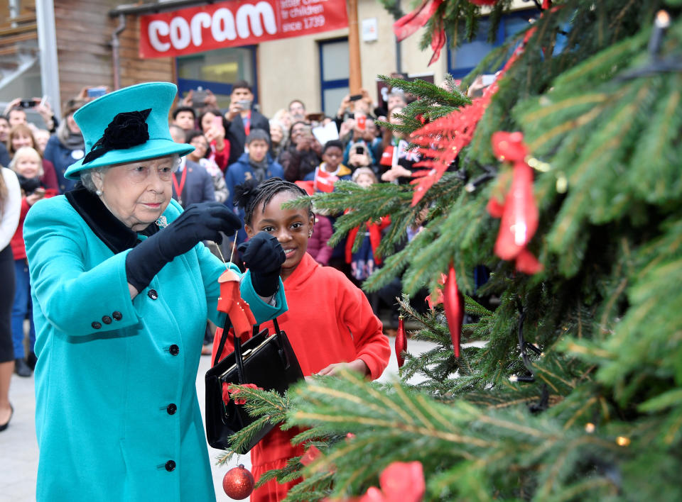 Queen Elizabeth II and Shylah Gordon, aged 8, attach a bauble to a Christmas tree during the opening of the Queen Elizabeth II centre at CORAM on December 05, 2018 in London, England.