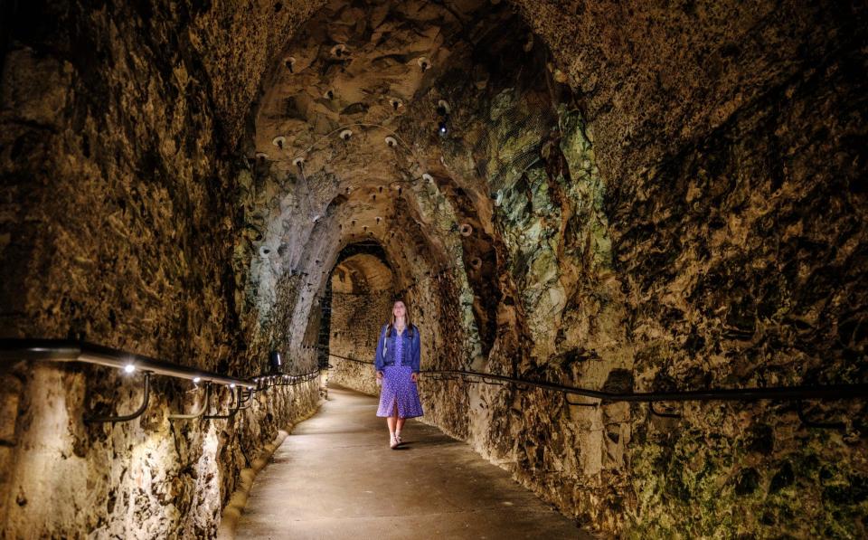 Woman walks through a tunnel carved out of stone