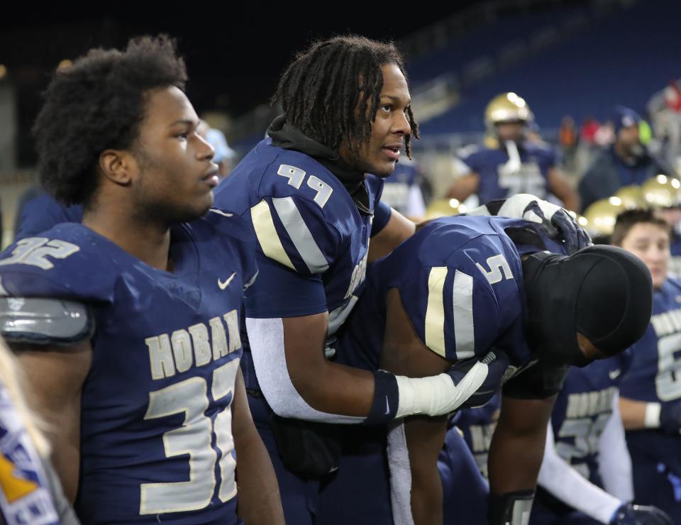 Hoban lineman Grant Thompson, center, comforts linebacker Devin Bell, right, after losing to Toledo Central Catholic in the Division II state final, Dec. 1, 2022, in Canton.