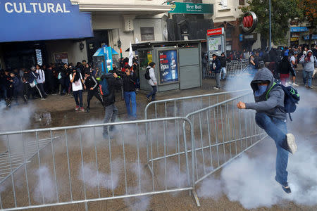 A demonstrator attempts to kick a tear gas canister during an unauthorized march called by secondary students to protest against government education reforms in Santiago, Chile, May 26, 2016. REUTERS/Ivan Alvarado