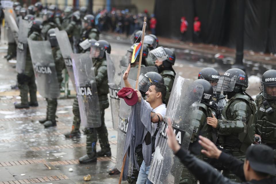 A man attempts to stop anti-government protesters from throwing rocks at the police during a nationwide strike, at Bolivar square in downtown Bogota, Colombia, Thursday, Nov. 21, 2019. Colombia's main union groups and student activists called for a strike to protest the economic policies of Colombian President Ivan Duque government and a long list of grievances. (AP Photo/Fernando Vergara)