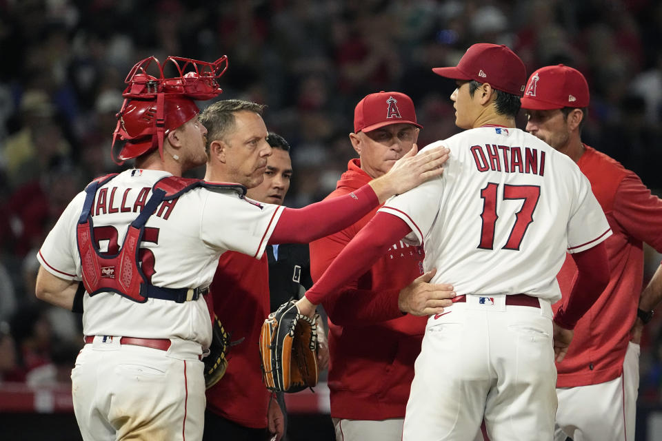 Los Angeles Angels starting pitcher Shohei Ohtani, second from right, gets a pat on the back from catcher Chad Wallach, left, as he is taken out during the seventh inning of a baseball game against the Chicago White Sox Tuesday, June 27, 2023, in Anaheim, Calif. (AP Photo/Mark J. Terrill)