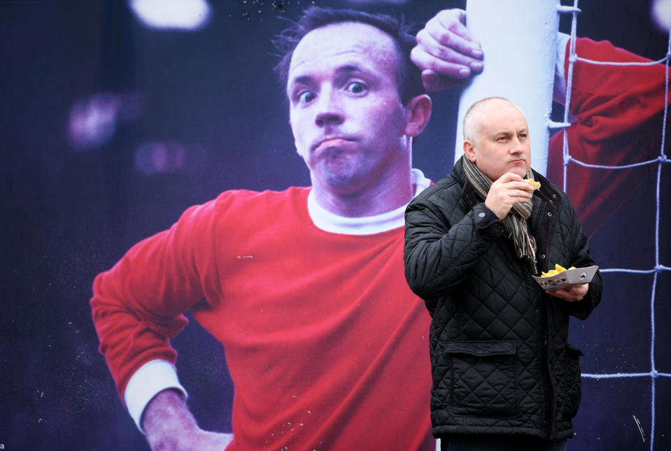 <p>United legend Nobby Stiles guides a fan to the ground </p>