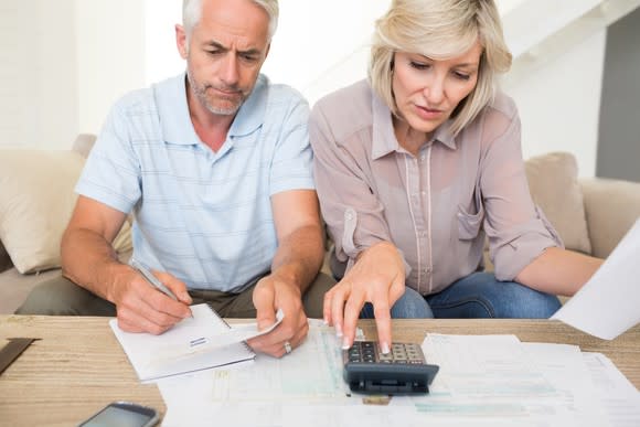 Old couple looking at financial documents and using a calculator