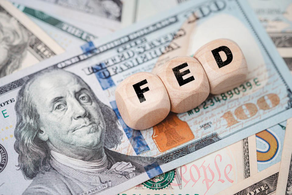 Dice spelling out "FED" for Federal Reserve on top of several bills.