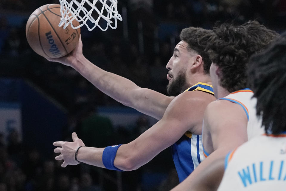 Warriors guard Klay Thompson, left, goes to the basket in front of Oklahoma City Thunder guard Josh Giddey, center, and forward Jalen Williams, right, in the first half of an NBA basketball game Monday, Jan. 30, 2023, in Oklahoma City. (AP Photo/Sue Ogrocki)