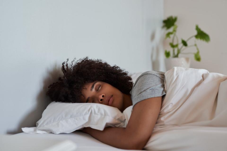 young woman lying fast asleep in her comfortable bed at home in the early morning