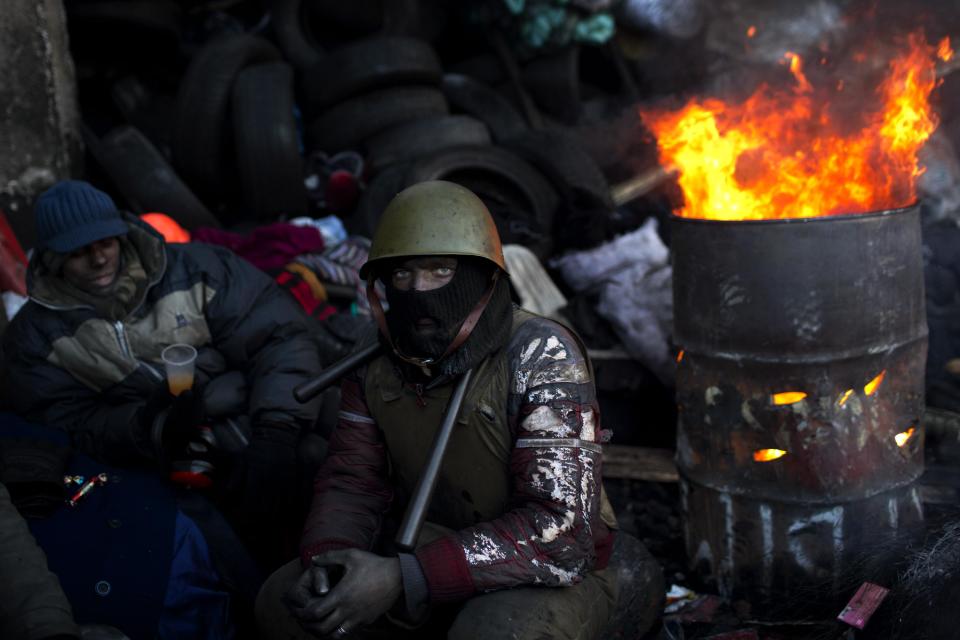 An opposition supporter looks on as he warms himself next to a fire in a barricade near Kiev's Independence Square, the epicenter of the country's current unrest, Ukraine, Friday, Jan. 31, 2014. Ukraine's embattled president Viktor Yanukovych is taking sick leave as the country's political crisis continues without signs of resolution. (AP Photo/Emilio Morenatti)