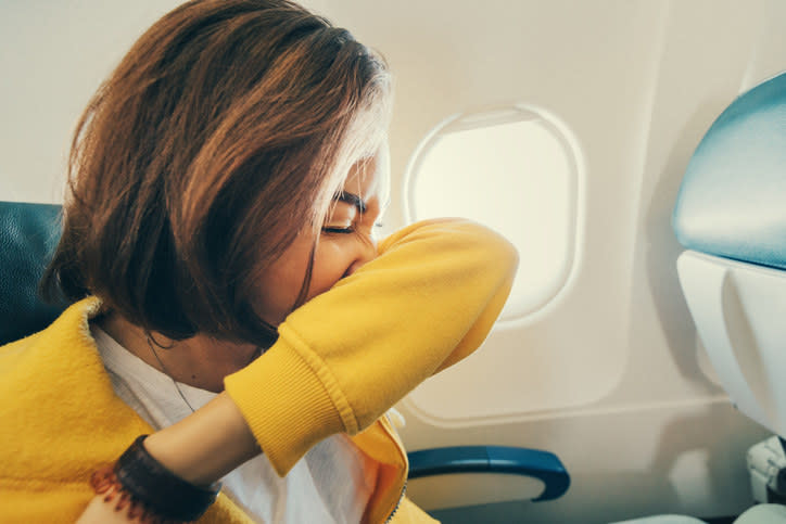 A woman sneezing on a plane