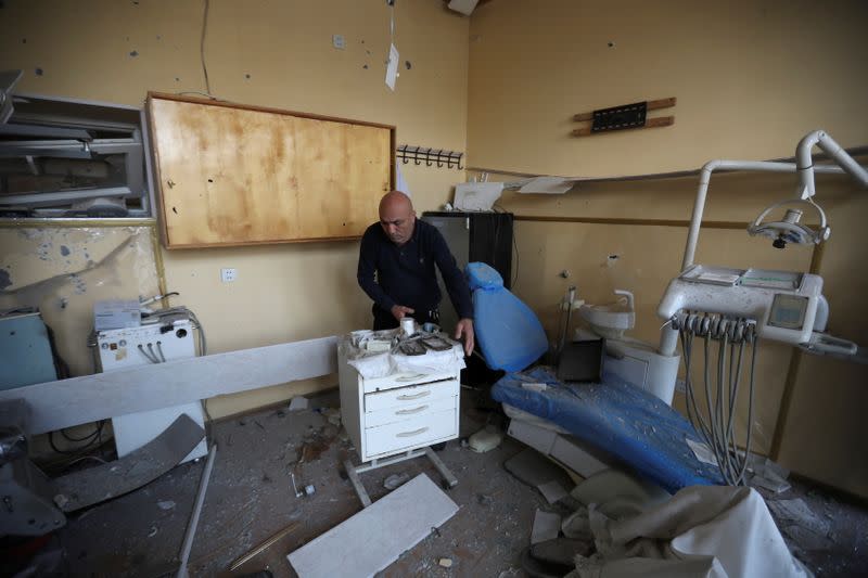A man removes debris inside a medical room following shelling in Barda