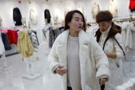 A customer tries on a mink fur coat in a store selling mink fur clothing at a shopping mall in Shangcun