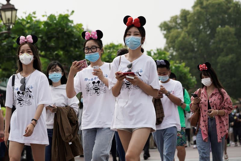 Visitors wearing protective face masks walk along the Shanghai Disney Resort as the Shanghai Disneyland theme park reopens following a shutdown due to the coronavirus disease (COVID-19) outbreak, in Shanghai