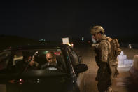 In this April 2, 2019 photo, an Iraqi army 20th division soldier asks for documents at a checkpoint near Badoush, Iraq. A year and a half after the Islamic State group was declared defeated in Iraq, the militants still evoke fear in the lands of their former so-called caliphate across northern Iraq. The fighters, hiding in caves and mountains, emerge at night to carry out kidnappings, killings and roadside ambushes, aimed at intimidating locals, silencing informants and restoring the extortion rackets that financed IS's rise to power six years ago. (AP Photo/Felipe Dana)