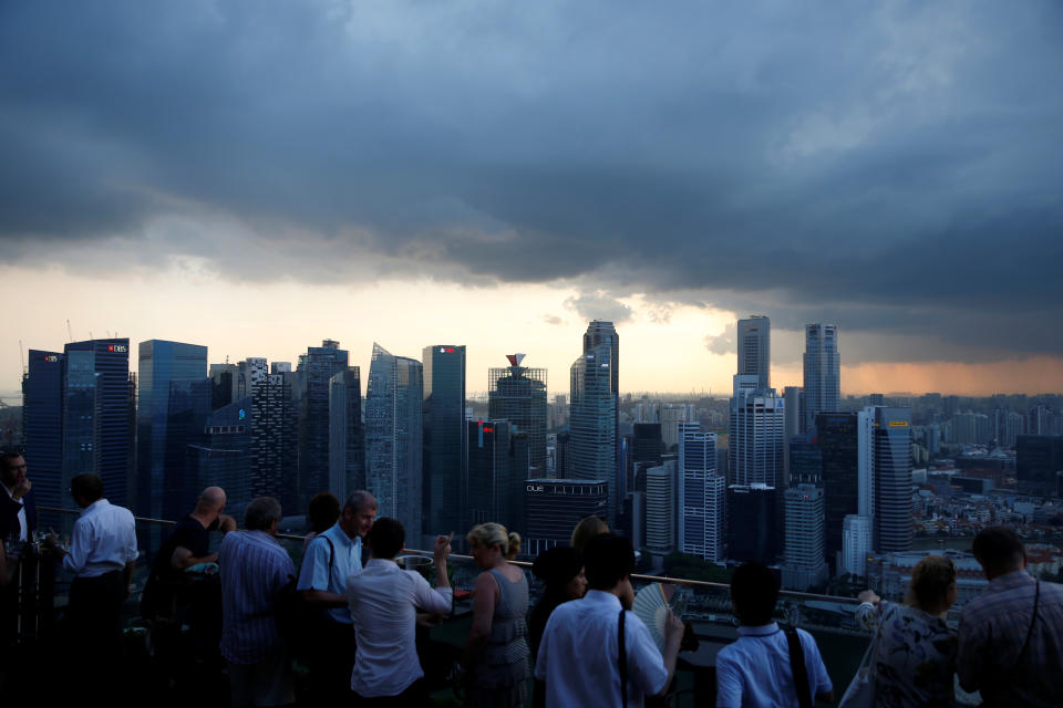 Tourists have drinks at a hotel rooftop bar as clouds gather over the central business district in Singapore June 6, 2016. REUTERS/Edgar Su 