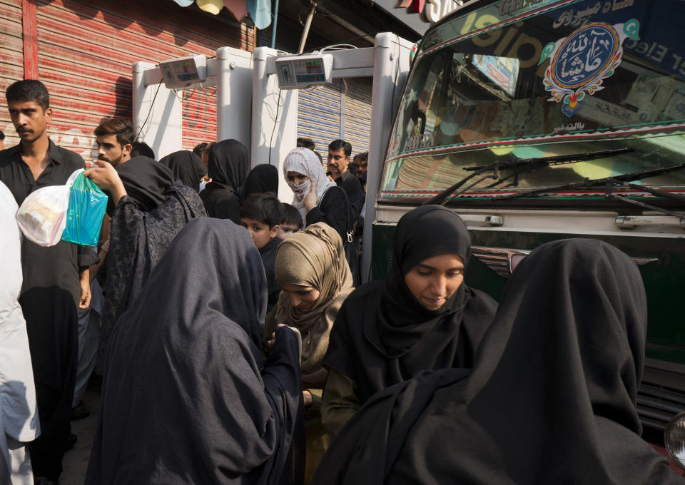 In this Tuesday, Oct. 30, 2018, photo police officers search Shiite Muslims who arriving to attend their religious congregation in Rawalpindi, Pakistan. Synagogues, mosques, churches and other houses of worship are routinely at risk of attack in many parts of the world. And so worshippers themselves often feel the need for visible, tangible protection even as they seek the divine. (AP Photo/B.K. Bangash)