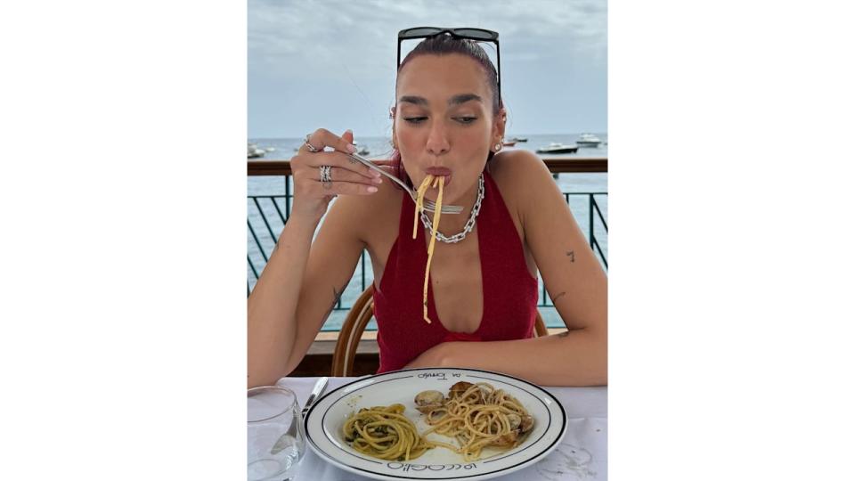 Dua Lipa eats pasta in Italy in a red top and diamond jewellery