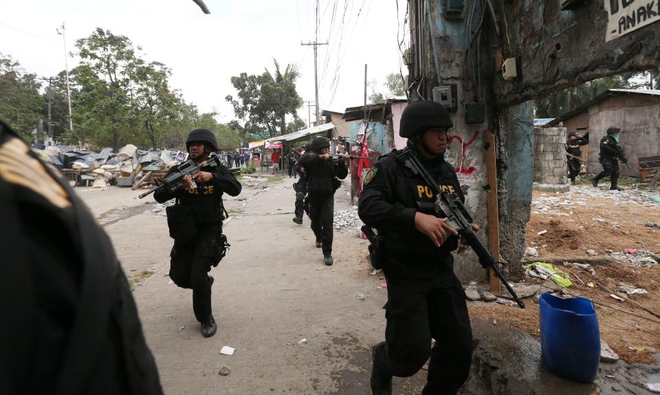 epa04044205 Filipino policemen from the Special Weapons And Tactics (SWAT) team chase informal settlers during a demolition of shanties at Sitio San Roque in Quezon City, east of Manila, Philippines, 27 January 2014. Throwing rocks, pillboxes, and even human waste, illegal settlers barricaded the demolition team in Baranggay Bagong Pag-asa. Four residents were arrested and twelve were reported injured. Residents report receiving cash from 300 to 450 US dollar in exchange for their voluntary relocation. Earlier, hundreds of the urban poor marched to the city hall in protest of the demolition that will pave the way for the rise of a business district. EPA/DENNIS M. SABANGAN