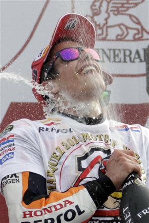 Honda MotoGP rider Spanish Marc Marquez celebrates on podium after becoming the youngest MotoGP world champion at the end of the Valencia Motorcycle Grand Prix at the Ricardo Tormo racetrack in Cheste, near Valencia, November 10, 2013. REUTERS/Heino Kalis