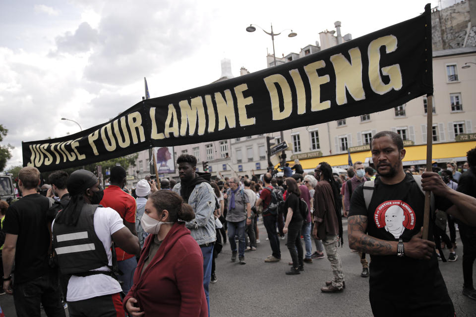 People march holding a banner during a protest in memory of Lamine Dieng, a 25-year-old Franco-Senegalese who died in a police van after being arrested in 2007, in Paris, Saturday, June 20, 2020. Multiple protests are taking place in France on Saturday against police brutality and racial injustice, amid weeks of global anger unleashed by George Floyd's death in the US. (AP Photo/Christophe Ena)