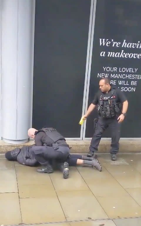 A police officer points a taser while the other holds a man down outside the Arndale shopping center, where several people were stabbed - Credit: JOHN GREENHALGH
