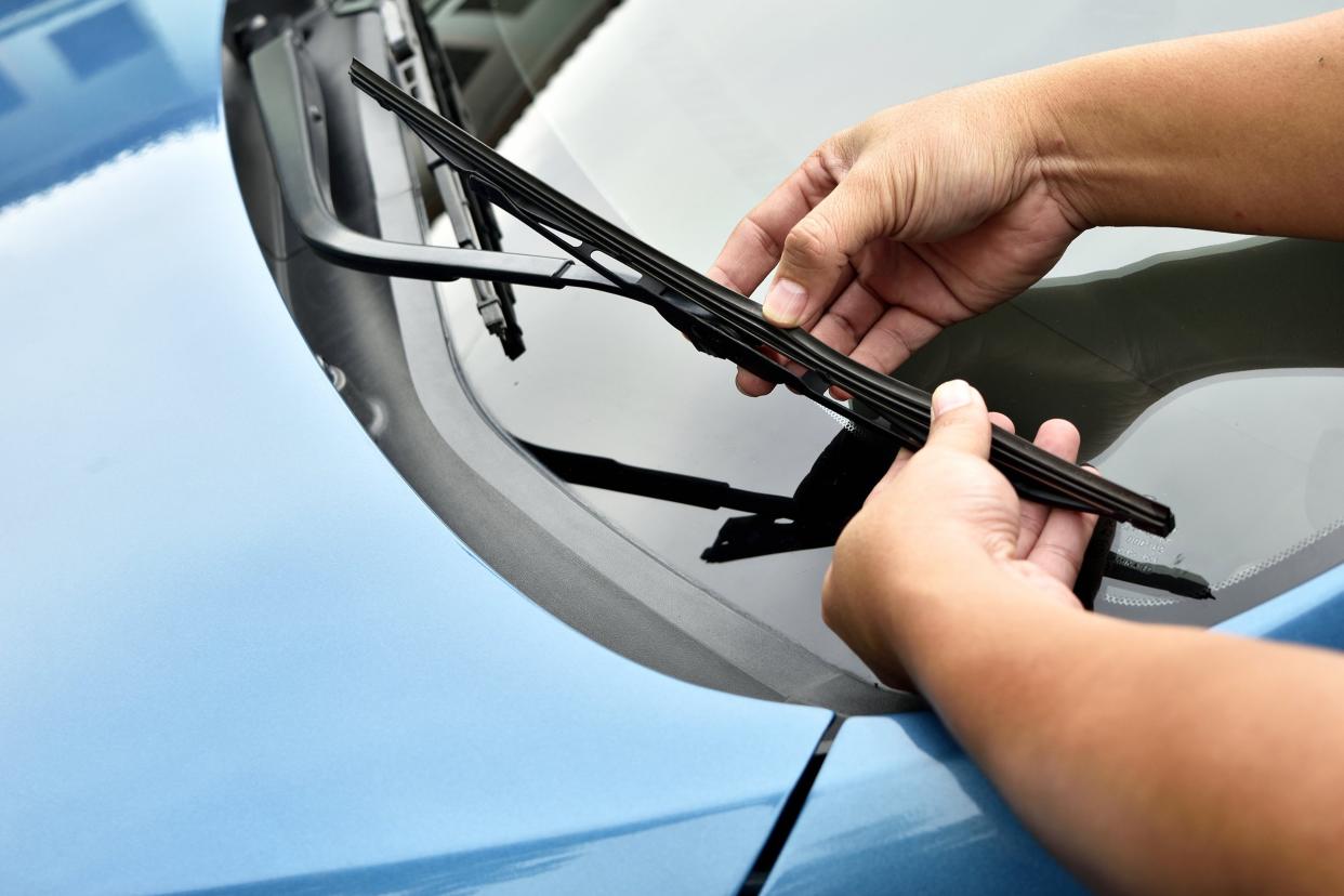 man hand picking up windscreen wiper on car