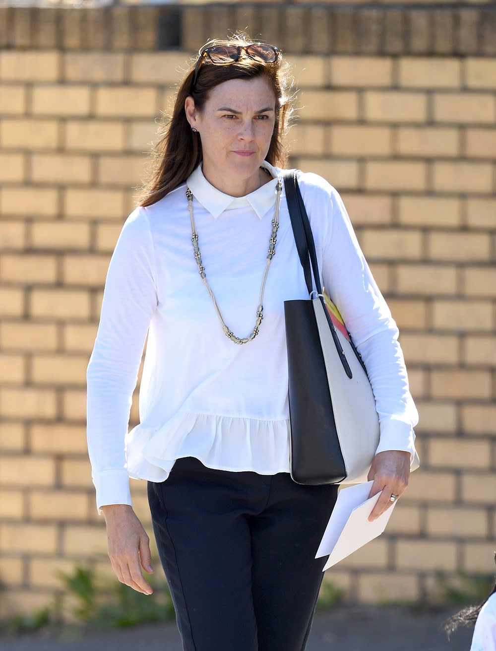 Samantha Cohen wearing a long-sleeved white blouse and dark pants