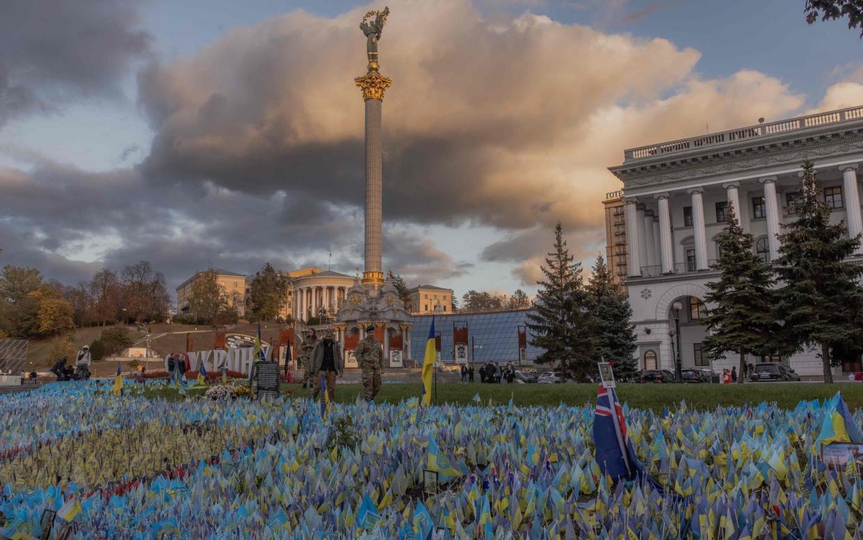 Pedestrians wearing military uniforms commemorate fallen Ukrainian soldiers at Independence Square in Kyiv