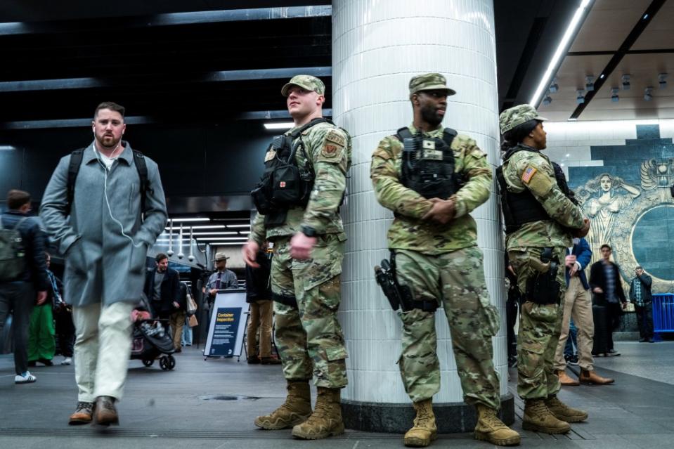 Members of the New York State National Guard keep an eye on commuters as they stand guard in a checkpoint inside the entrance of a subway station in New York City on March 7, 2024. REUTERS