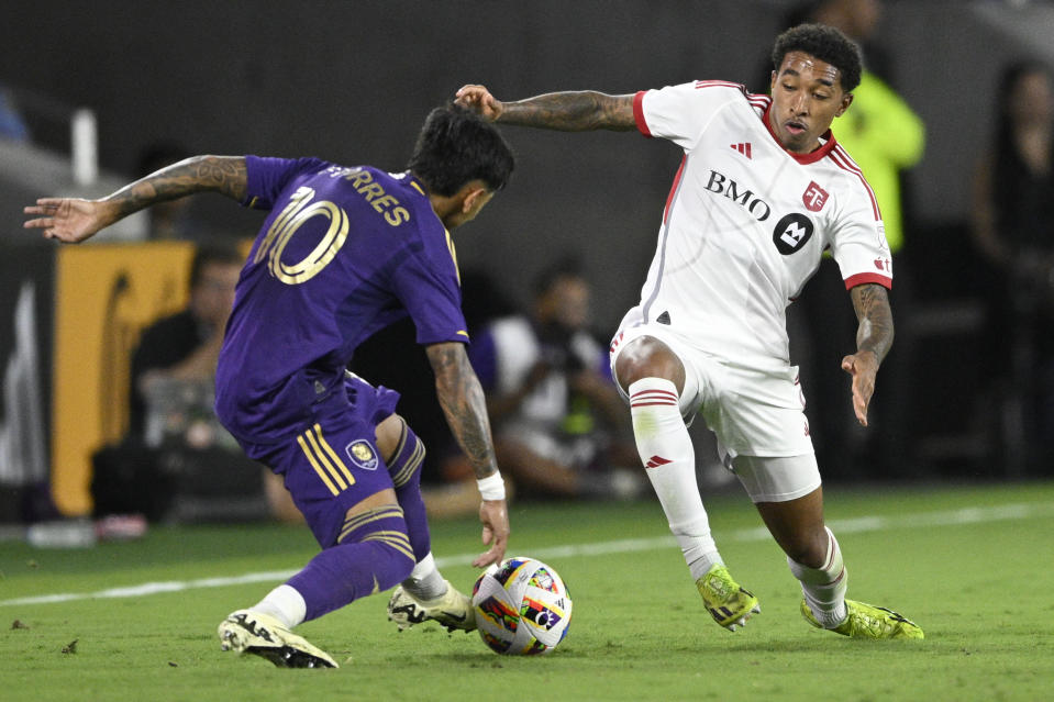 Orlando City forward Facundo Torres (10) and Toronto FC midfielder Jahkeele Marshall-Rutty compete for the ball during the first half of an MLS soccer match Saturday, April 27, 2024, in Orlando, Fla. (AP Photo/Phelan M. Ebenhack)