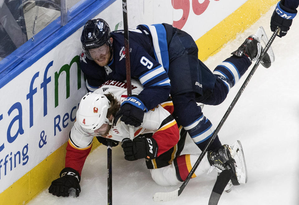 Calgary Flames' Rasmus Andersson (4) is checked by Winnipeg Jets' Andrew Copp during the third period of an NHL qualifying round game, in Edmonton, Alberta, Thursday, Aug. 6, 2020. (Jason Franson=/The Canadian Press via AP)