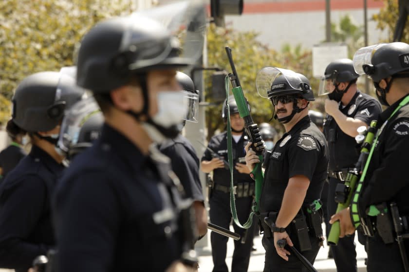 LOS ANGELES, CA - AUGUST 14, 2021 - - Los Angeles police officers keep an eye out after advocates against vaccine mandates and pro-vaccine advocates confronted each other in front of the L.A.P.D. Headquarters in downtown Los Angeles on August 14, 2021. A man was stabbed during the melee and taken by paramedics to a nearby hospital. No arrests were made in the confrontation. (Genaro Molina / Los Angeles Times)