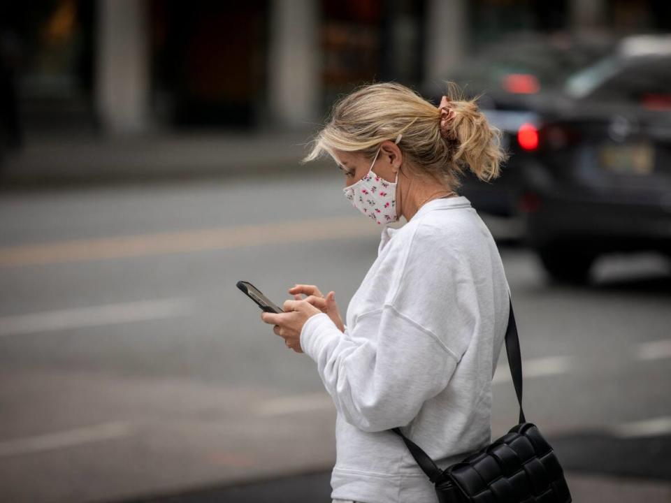 A woman looks at her cellphone while walking in downtown Vancouver, British Columbia on Monday, Oct. 4, 2021.  (Ben Nelms/CBC - image credit)