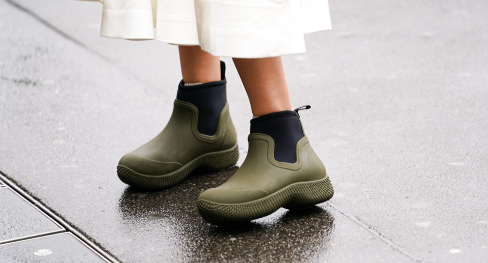 woman wearing white skirt and short green rain boots with black details