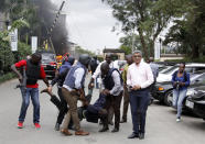 Security forces help a man at the scene of a blast in Nairobi, Kenya Tuesday, Jan. 15, 2019. Terrorists attacked an upscale hotel complex in Kenya's capital Tuesday, sending people fleeing in panic as explosions and heavy gunfire reverberated through the neighborhood. (AP Photo/Khalil Senosi)