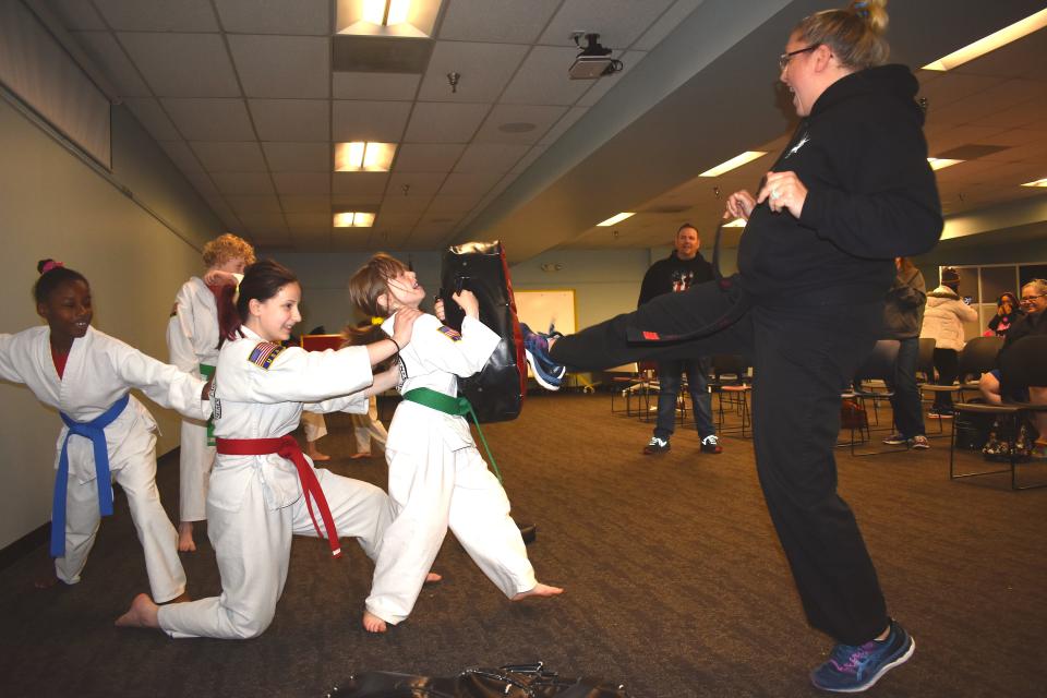 Instructor Amber Lilly, right, of Black Dragon's Den Martial Arts Academy in Adrian, demonstrates a front kick technique during the Adrian District Library's "Ninja Saturday at the Library" program April 30. Assisting with Lilly's front kick demonstrations are students Dailey Williams, Miranda Stone and Savannah Schettler.