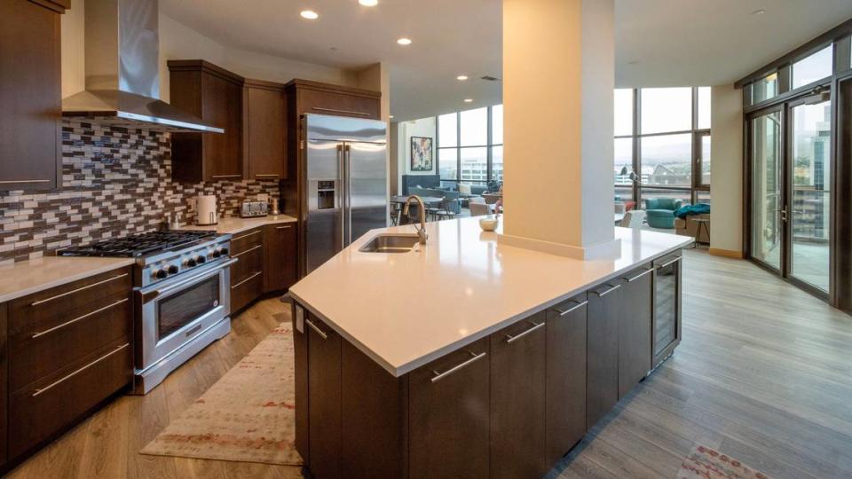 The penthouse kitchen has quartz counters and leads onto the deck, at right.