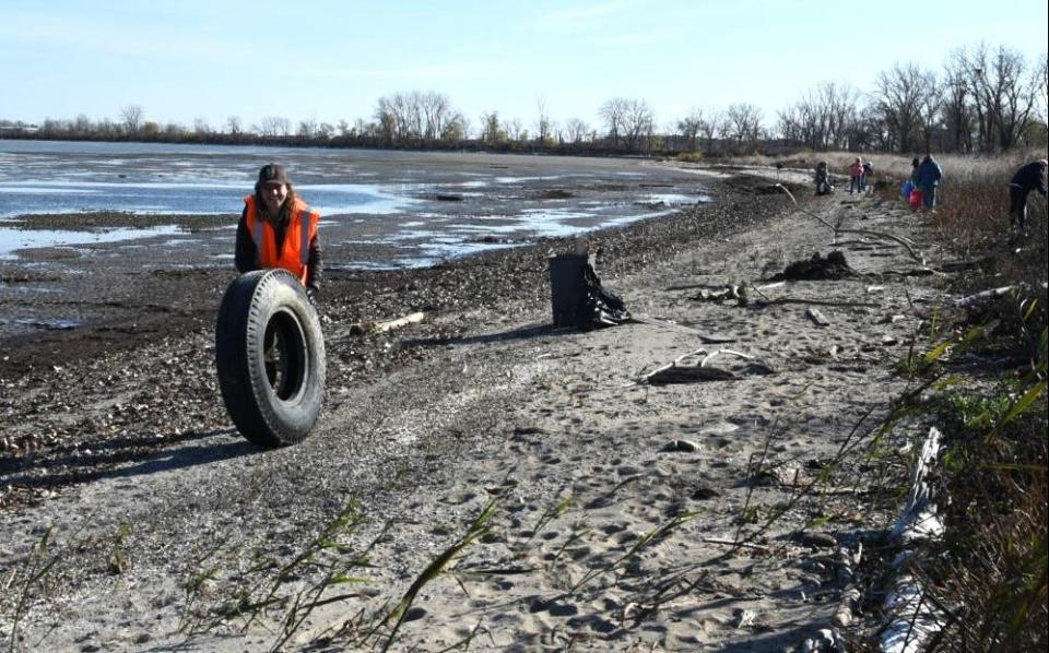 Basia Gowin, a park ranger with the Ottawa National Wildlife Refuge, pushes a tire from a beach at Cedar Point National Wildlife Refuge in nearby Oregon.