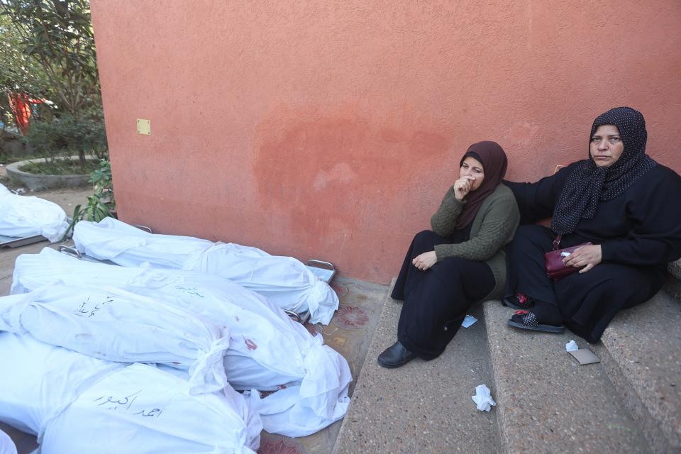 Women sit next to shrouded bodies of relatives killed following Israeli strikes at Khan Yunis's Nasser hospital in the southern Gaza Strip on Dec. 9, 2023, amid continuing battles between Israel and the Palestinian militant group Hamas.