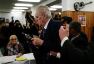 Czech President Milos Zeman arrives to cast a vote during the country's direct presidential election as a Femen activist is escorted by Zeman's bodyguards at a polling station in Prague, the Czech Republic January 12, 2018. REUTERS/David W Cerny