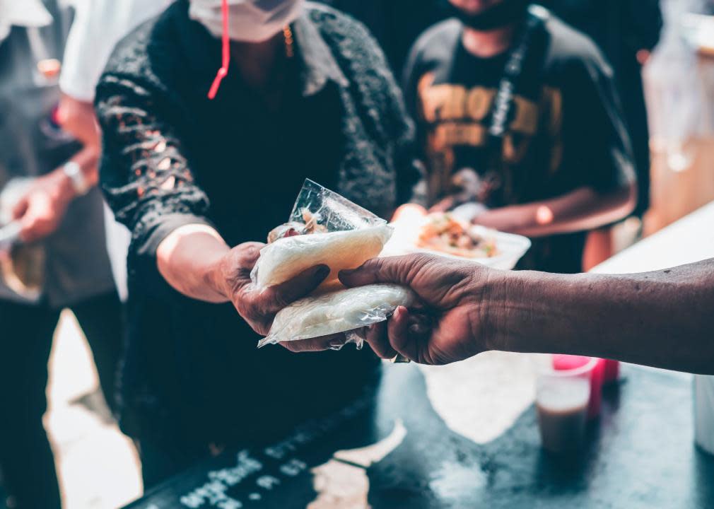 Hands handing out food to a passerby.