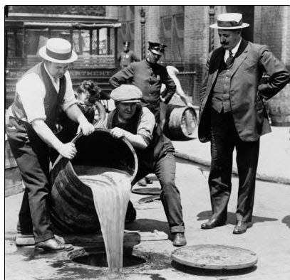 Law enforcement officials pour whiskey down the drain during prohibition.