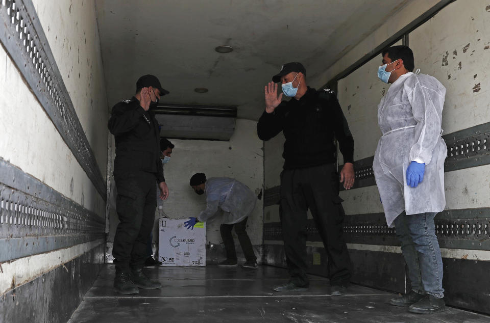 Medics and police officers guard a shipment of the Russian Sputnik V vaccine inside a truck at the Kerem Shalom border crossing, in Rafah, Gaza Strip, Wednesday, Feb. 17, 2021. The Palestinian Authority said Wednesday that it dispatched the first shipment of coronavirus vaccines to the Hamas-ruled Gaza Strip, two days after accusing Israel of preventing it from sending the doses amid objections from some Israeli lawmakers. (AP Photo/Adel Hana)