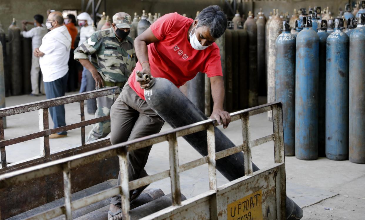 Workers load oxygen cylinders at a charging station on the outskirts of Prayagraj, India, Friday, April 23, 2021. India put oxygen tankers on special express trains as major hospitals in New Delhi on Friday begged on social media for more supplies to save COVID-19 patients who are struggling to breathe. India's underfunded health system is tattering as the world's worst coronavirus surge wears out the nation, which set another global record in daily infections for a second straight day with 332,730. (AP Photo/Rajesh Kumar Singh)