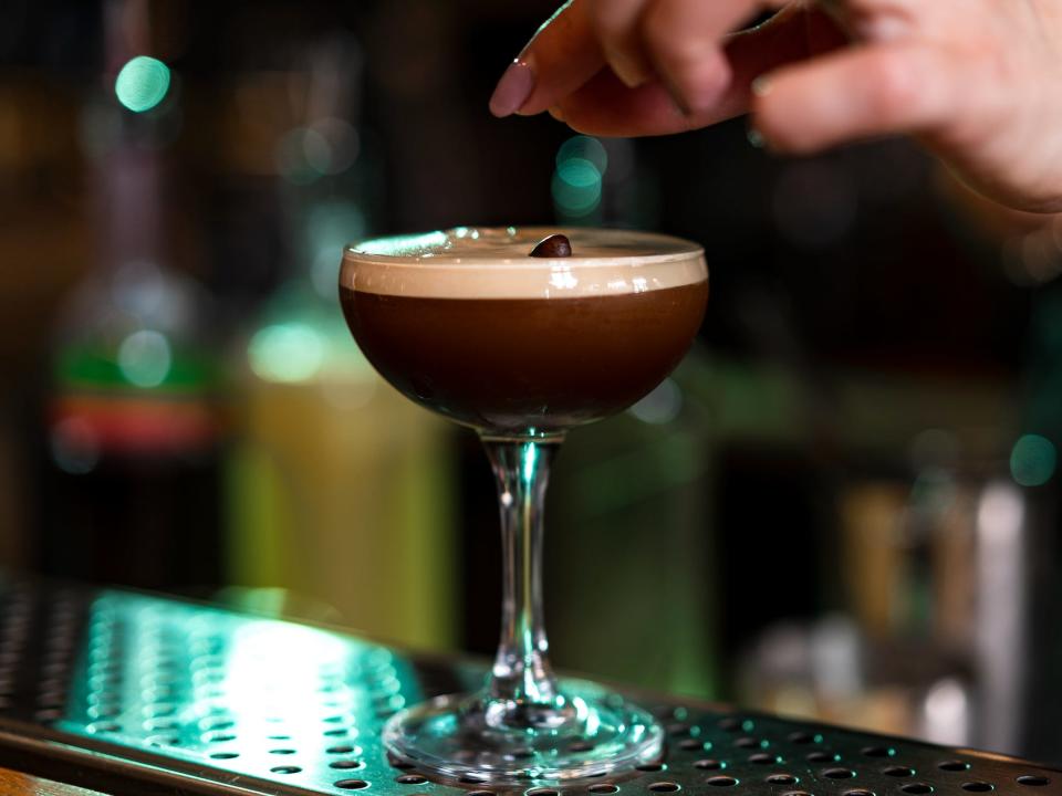 hand garnishing an espresso martini on a bar